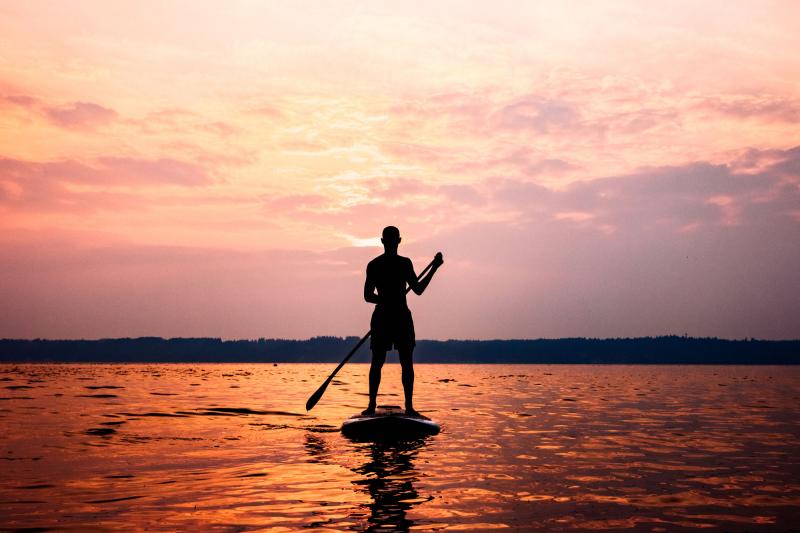 Silhouette of man on stand up paddle board at sunset